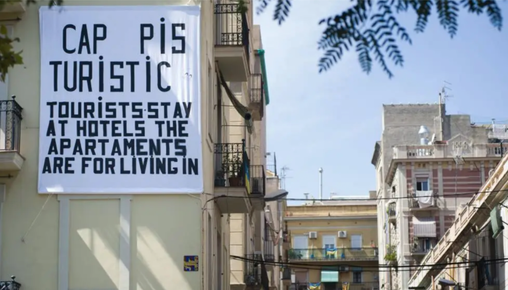 Airbnb and gentrification in Barcelona, illustrated through a sign on a building saying "tourists stay at hotels the apartments are for living"