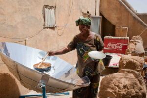 African woman cooking on a solar panel