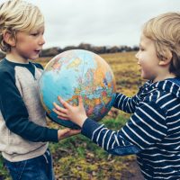 Two children passing a globe to each other